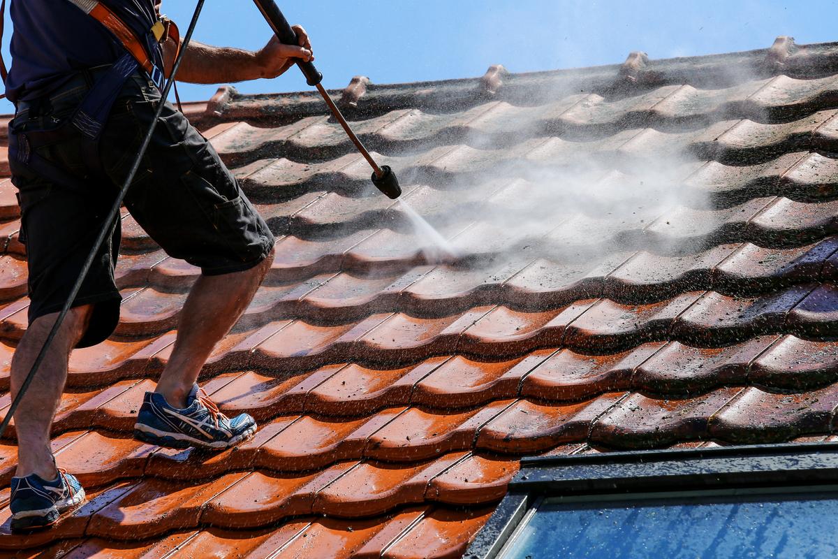 Profesionál čistící střechu pomocí vysokotlakové hadice